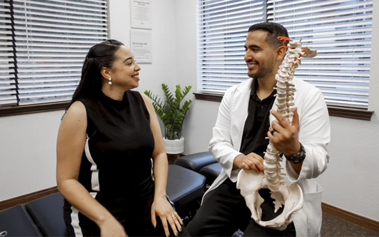 Dr. Jorge Ayala with spine structure and a patient during an evaluation session.