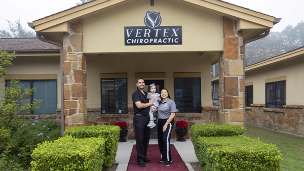 Dr. Jorge Ayala and family standing at the entrance of Vertex Chiropractic, showcasing a welcoming clinic environment.